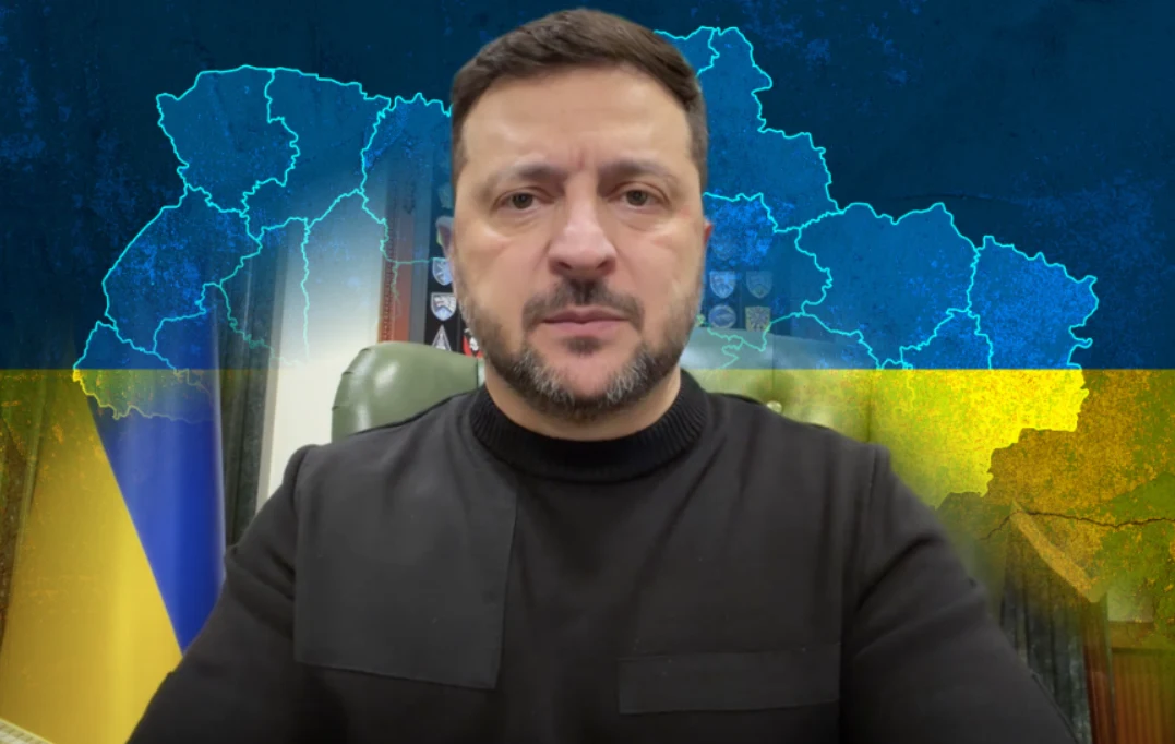 Wołodymyr Zełenski zareagował na doniesienia w sprawie planów ogłoszenia wybór w Ukrainie Mężczyzna w czarnym swetrze siedzi przy biurku, w tle mapa Ukrainy na niebiesko-żółtym tle będącym kolorami flagi narodowej.