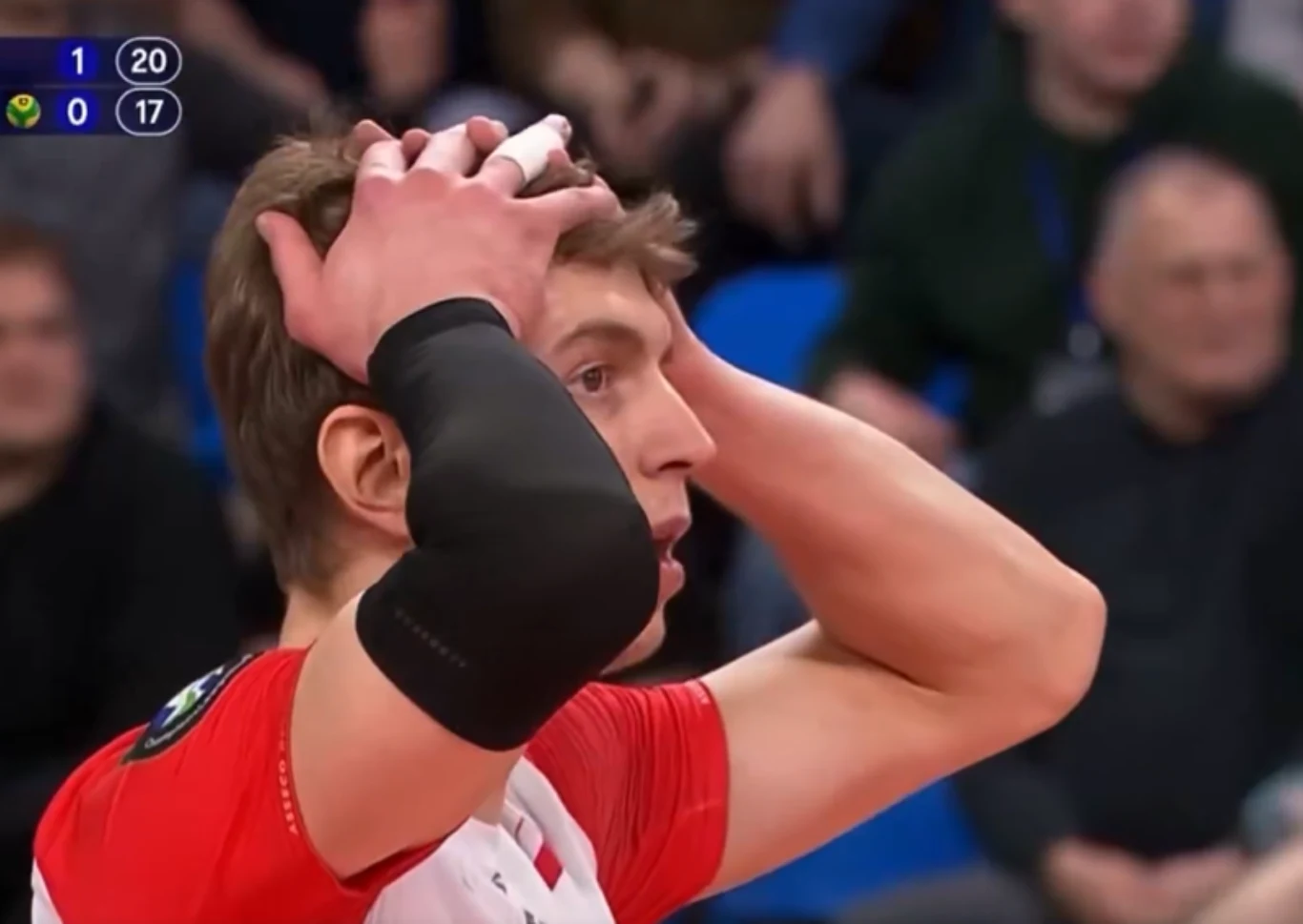 Artur Szalpuk, przyjmujący Asseco Resovii Rzeszów, był jedną z czołowych postaci meczu z Aluron CMC Wartą Zawiercie. Ale też nie mógł się pogodzić z jedną z decyzji sędziego Siatkarz w czerwono-białym stroju z opaską na ramieniu i opatrunkiem na palcu trzyma ręce na głowie w geście emocji podczas sportowego meczu, w tle widoczni kibice oraz wynik na tablicy punktowej.