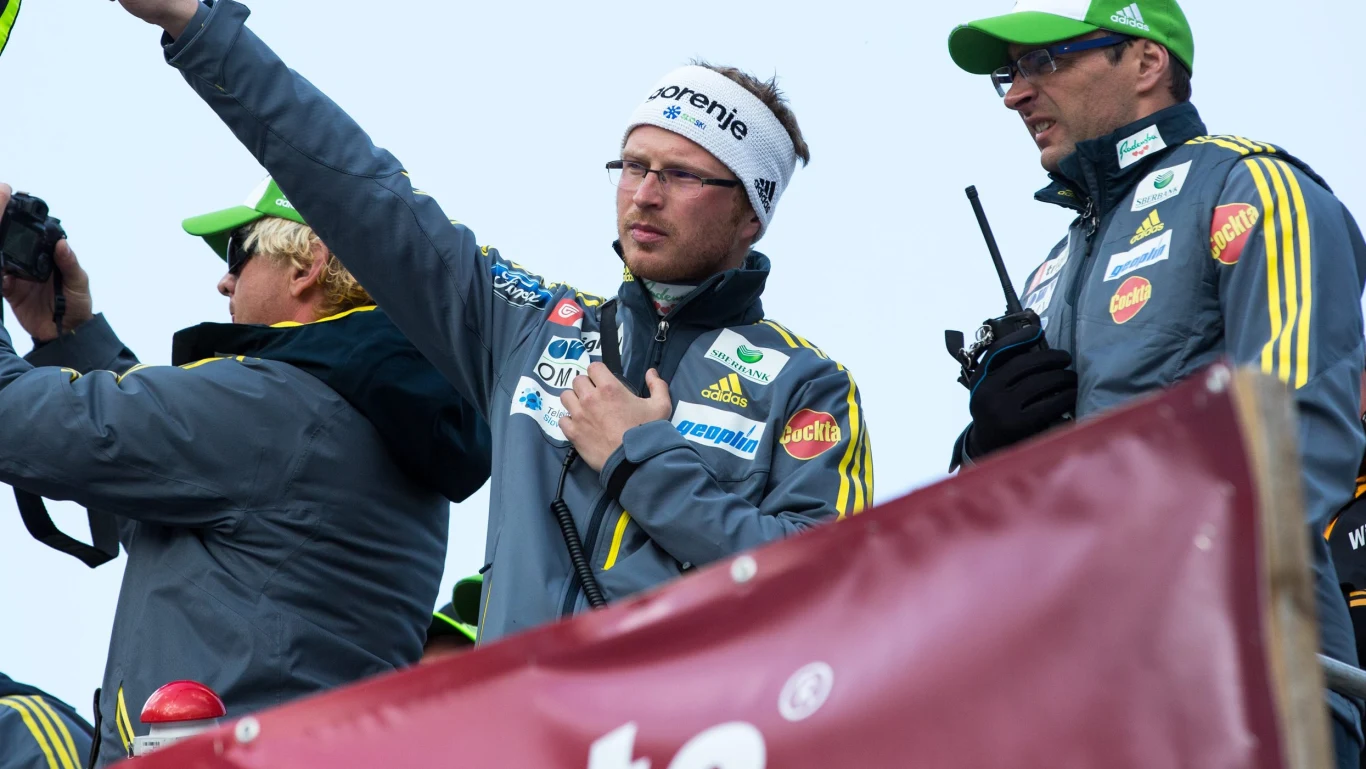 Igor Medved, tutaj jeszcze w czasach współpracy z kadrą Słowenii Grupa mężczyzn ubranych w kurtki sportowe oraz czapki i opaski z logo sponsorów, jeden z nich gestykuluje unosząc ramię, drugi trzyma krótkofalówkę, wszyscy skupieni na wydarzeniu sportowym.