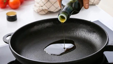 Kucharz leje olej na patelnię