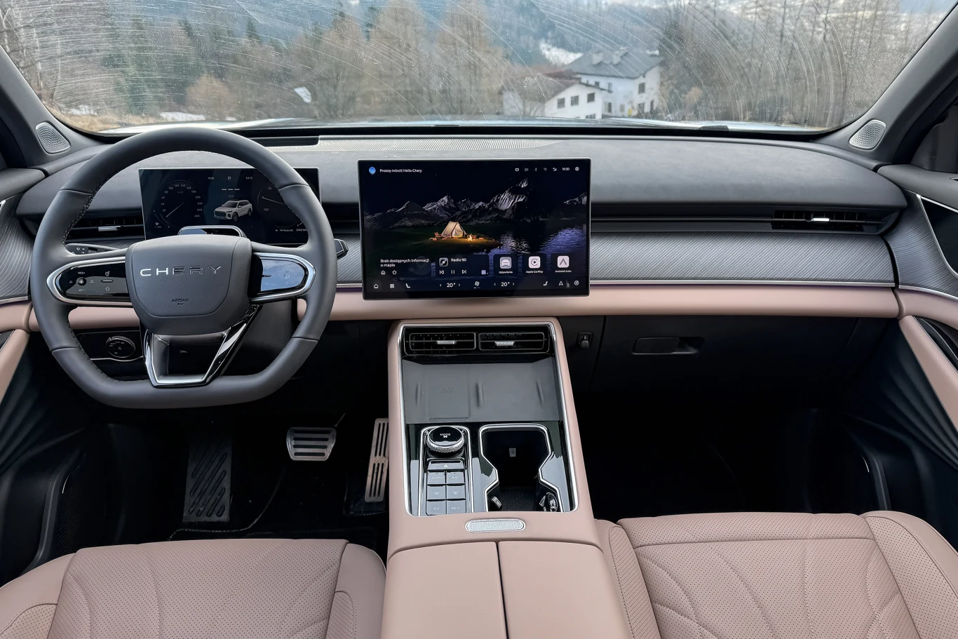 Luksusowe wnętrze samochodu z nowoczesnym, dużym ekranem na konsoli środkowej, skórzane fotele oraz eleganckie wykończenia, widok na kierownicę i panele sterowania.