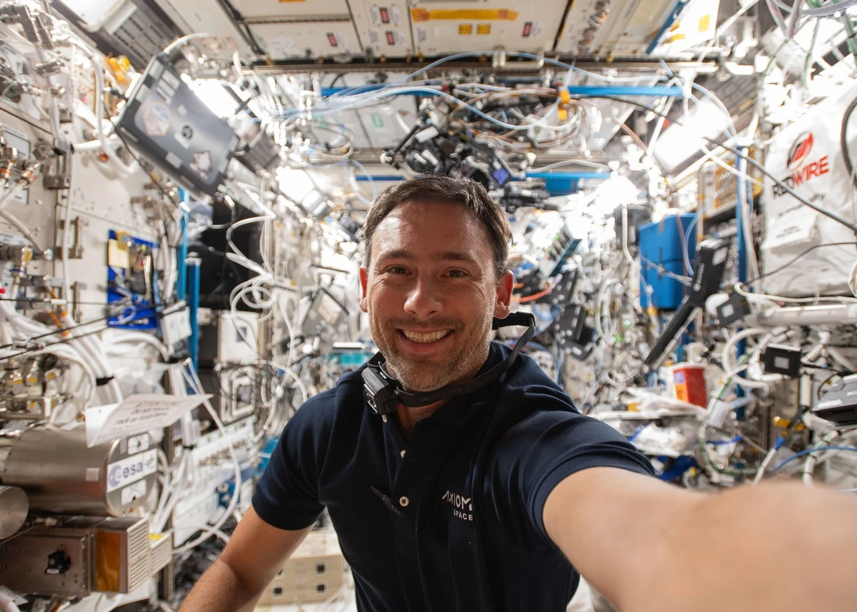 Testował go polski astronauta na ISS. Interfejs mózg-komputer działa w kosmosie Astronauta uśmiechający się, wykonujący selfie we wnętrzu stacji kosmicznej, otoczony licznymi panelami, przewodami oraz urządzeniami badawczymi.