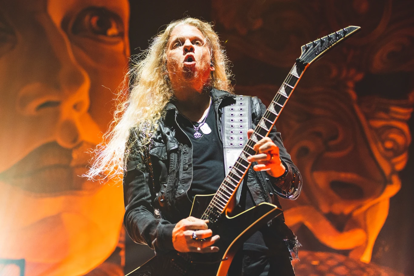 Jeff Loomis ogłosił nowy skład Nevermore Muzyk z długimi blond włosami grający na elektrycznej gitarze, ubrany w czarną kurtkę z ćwiekami, na tle efektownie oświetlonej sceny z wyrazistym malowidłem twarzy.