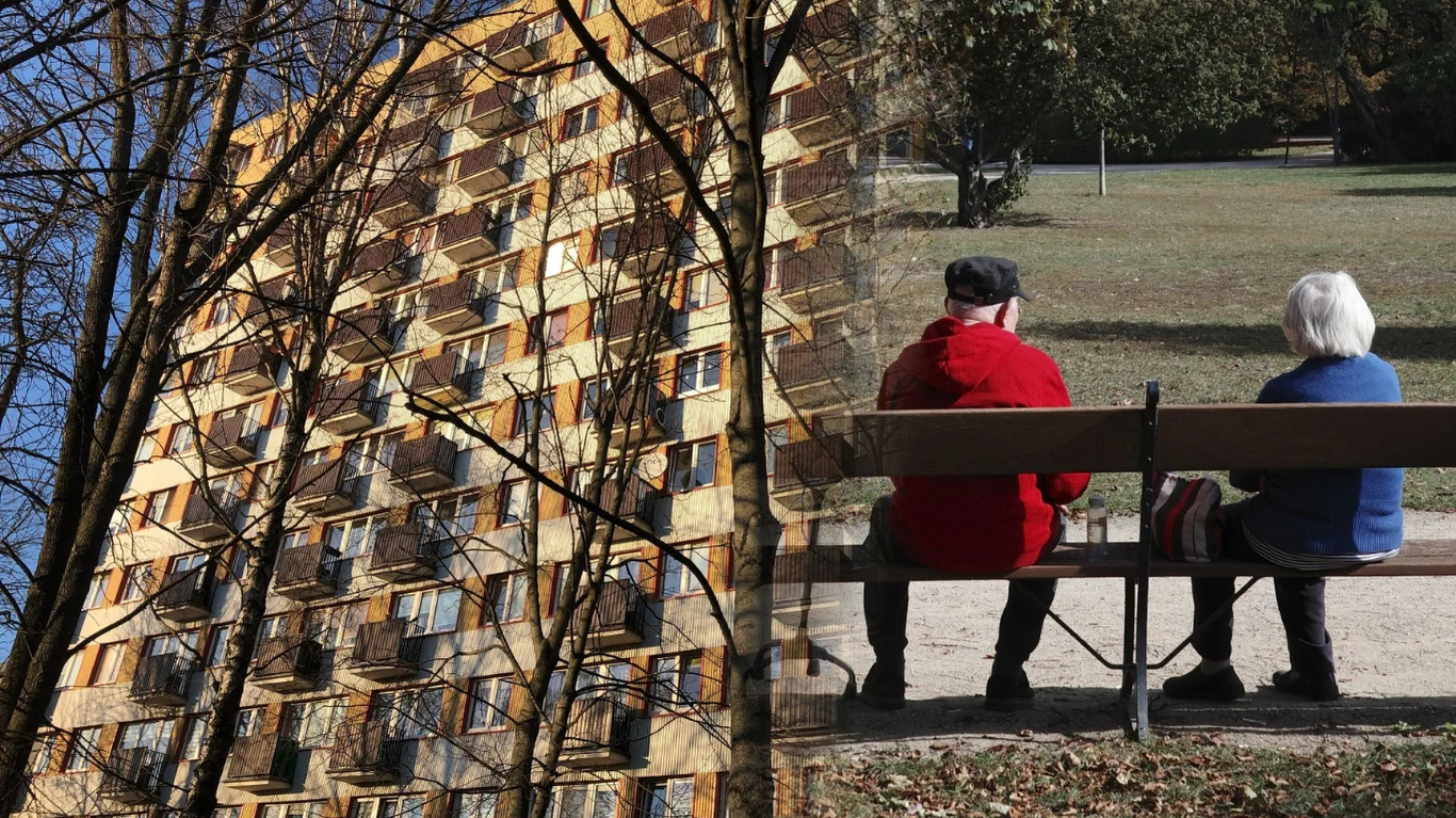 Seniorzy mówią o swoich obawach Dwie główne części obrazu: po lewej stronie fragment fasady bloku mieszkalnego z licznymi balkonami i gałęziami drzew na pierwszym planie, po prawej starsza para siedząca na ławce w parku, zwrócona tyłem do obiektywu, w otoczeniu zieleni.