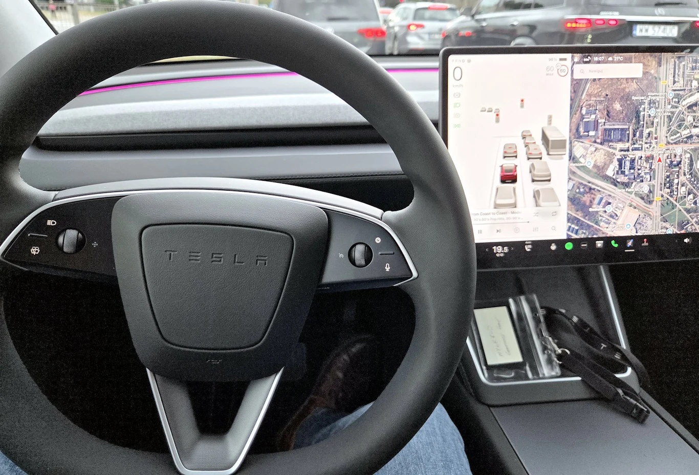 Chińczycy zmieniają prawo. Nowe wyposażenie obowiązkowe w autach ma skończyć z ekranozą Kierownica samochodu Tesla, duży dotykowy ekran komputera pokładowego wyświetlający mapę i informacje o aucie, klucz, dokumenty oraz nowoczesne wnętrze z widokiem na ruch uliczny za szybą.