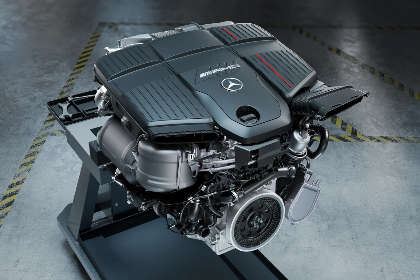 Nowoczesny silnik samochodowy Mercedes-AMG o rozbudowanej konstrukcji, z widocznym logo producenta i detalami technicznymi obudowy, ustawiony na metalowym stojaku w warsztacie lub hali produkcyjnej.