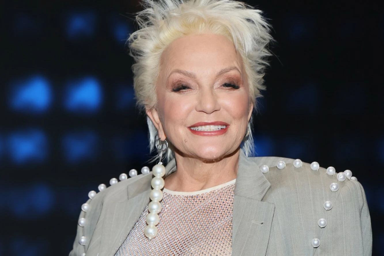 Małgorzata Ostrowska w grudniu 2025 r. pochowała męża Starsza kobieta z jasnymi, krótkimi włosami, uśmiechnięta, ubrana w jasną marynarkę ozdobioną perełkami na ramionach i siateczkowy top, na tle rozmytego, ciemnoniebieskiego tła.