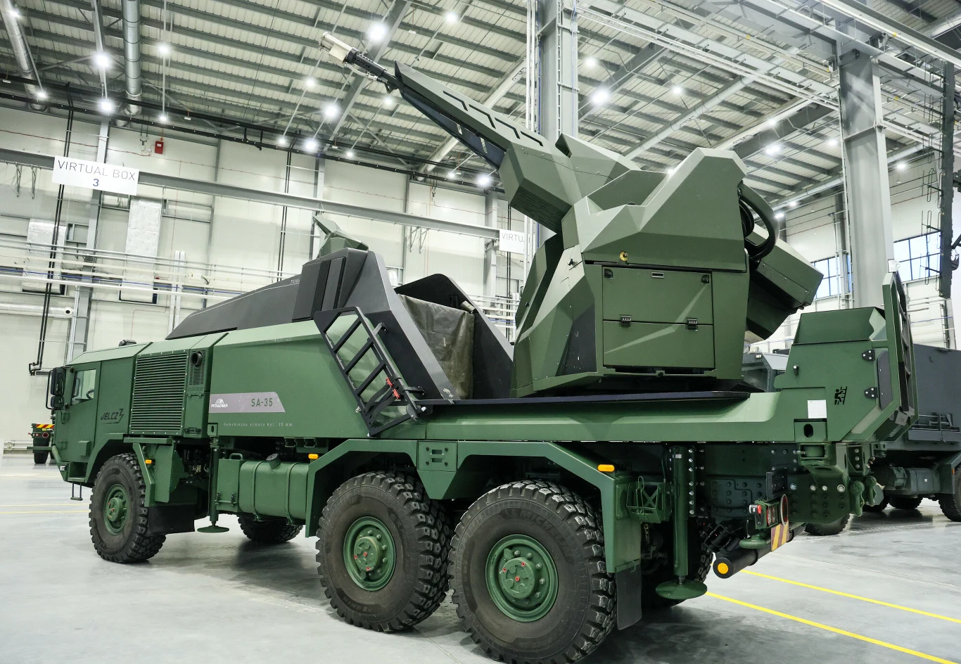 Plan wydatków środków z programu SAFE wydaje się imponujący. Rząd kreśli "listę zadań" Opancerzony pojazd wojskowy na sześciu kołach z zamontowaną automatyczną armatą przeciwlotniczą, ustawiony w nowoczesnej hali przemysłowej. Ściany i sufit obiektu wykonane z metalu i szkła, całość dobrze oświetlona.