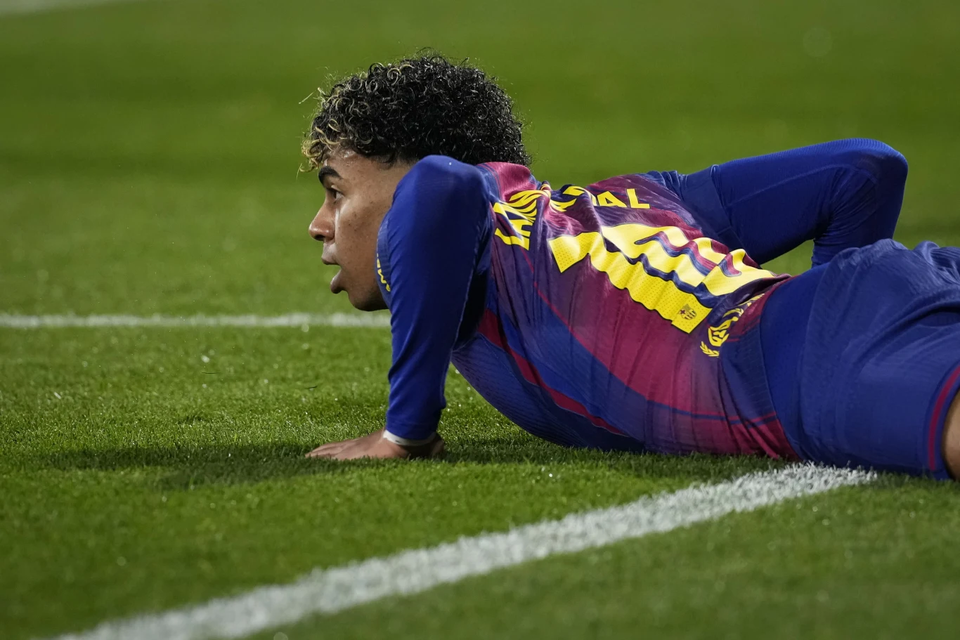 W doliczonym czasie gry pierwszej połowy Lamine Yamal nie wykorzystał rzutu karnego Piłkarz w stroju meczowym leży na murawie boiska, opierając się na łokciach, z twarzą skierowaną w stronę gry. W tle zielona trawa i linia boczna boiska.