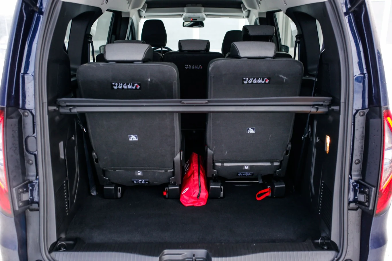 Przy rozłożonych wszystkich siedmiu fotelach w aucie mieści się 500 litrów bagażu. Wnętrze samochodu typu van widoczne od strony bagażnika, dwa tylne siedzenia w górnej pozycji, opuszczana półka nad przestrzenią bagażową, po środku umieszczona czerwona torba.