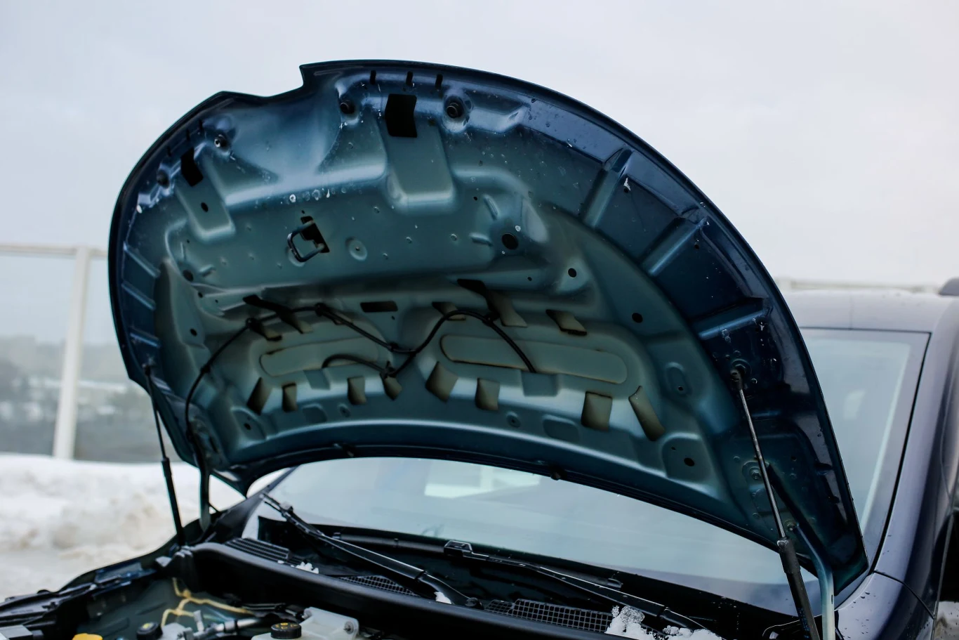 Patrząc na podniesioną maskę miałem skojarzenia bardziej z egzemplarzem przedprodukcyjnym niż seryjnie produkowanym samochodem. Otwarta maska samochodu osobowego z widoczną strukturą wewnętrzną, tło stanowi zimowy krajobraz oraz częściowo widoczna przednia szyba auta.