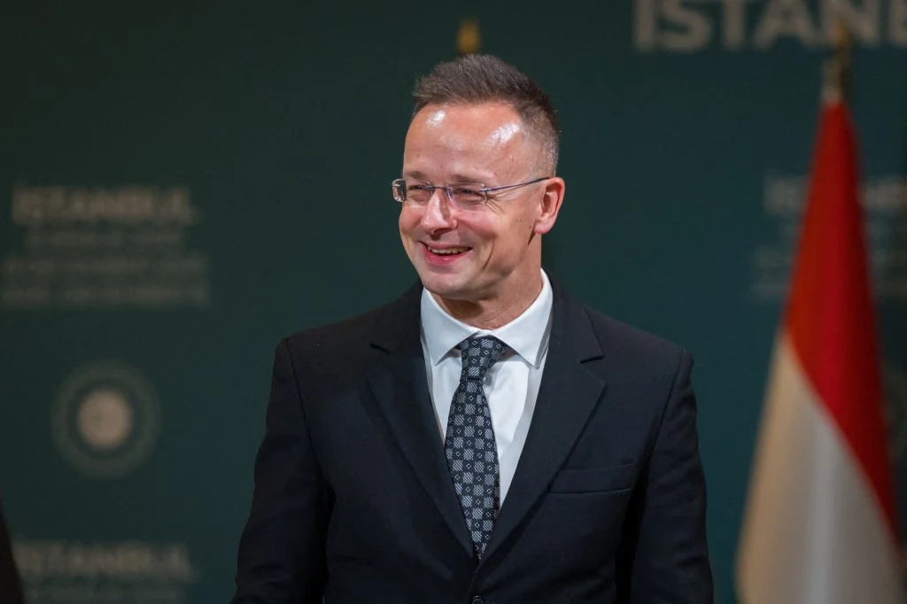 Szef MSZ Węgier Peter Szijjarto ostrzega o możliwej ingerencji w wybory Mężczyzna w okularach, garniturze i krawacie stoi na tle zielonej ściany z napisem ISTANBUL, obok widoczny fragment flagi.