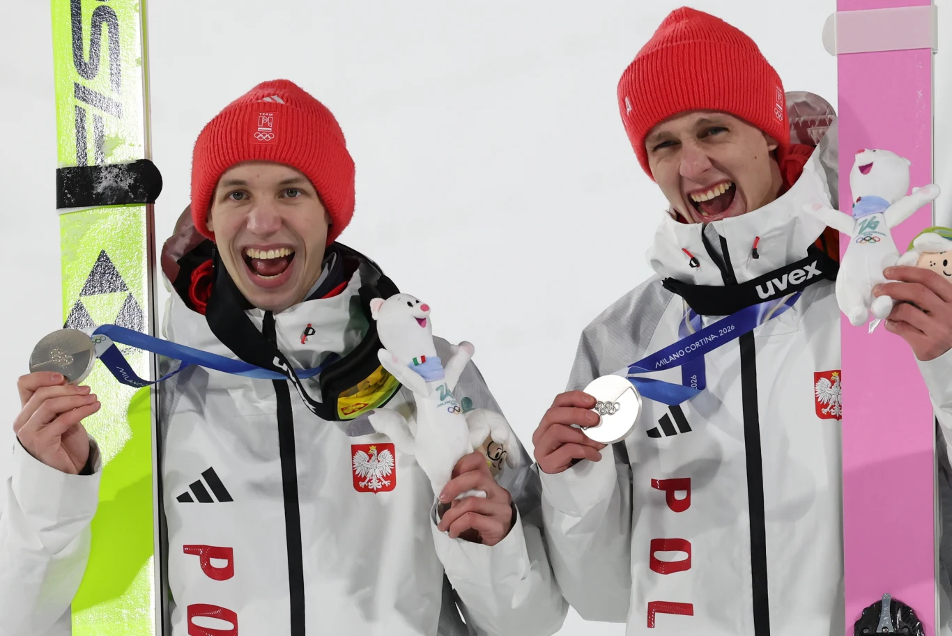 Sportowcy, którzy otrzymają tokeny w nagrodę za medale, muszą się liczyć z podatkiem Dwaj sportowcy w białych kurtkach z orłem, w czerwonych czapkach, trzymają srebrne medale oraz maskotki. Jeden z nich trzyma także narty. Obaj uśmiechnięci, w tle jasne światło.