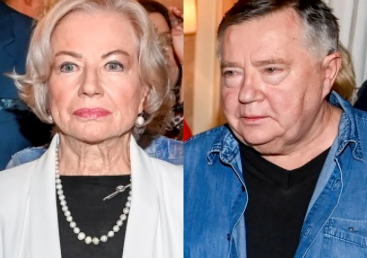 Bożena Dykiel, Mieczysław Hryniewicz Starsza kobieta w eleganckiej białej marynarce, ozdobiona perłowym naszyjnikiem i broszką, obok mężczyzna w niebieskiej koszuli na czarnym t-shircie. Oboje wpatrzeni w obiektyw, w tle niewyraźne sylwetki innych osób.