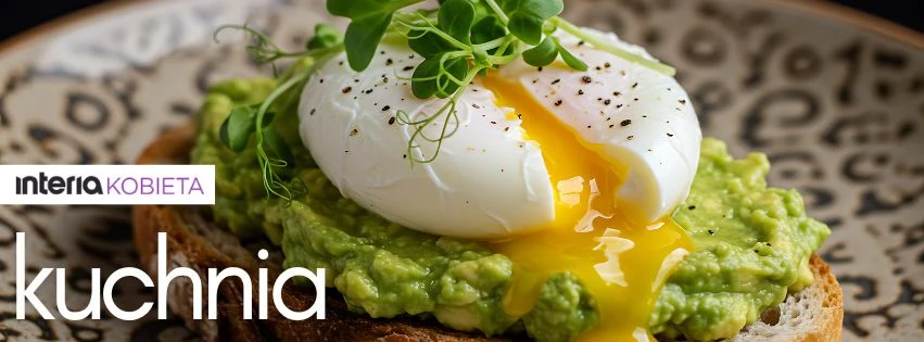 Kromka chleba z chrupiącą skórką posmarowana pastą z awokado, na której znajduje się jajko w koszulce z płynnym żółtkiem, całość posypana świeżo zmielonym pieprzem i udekorowana kiełkami.