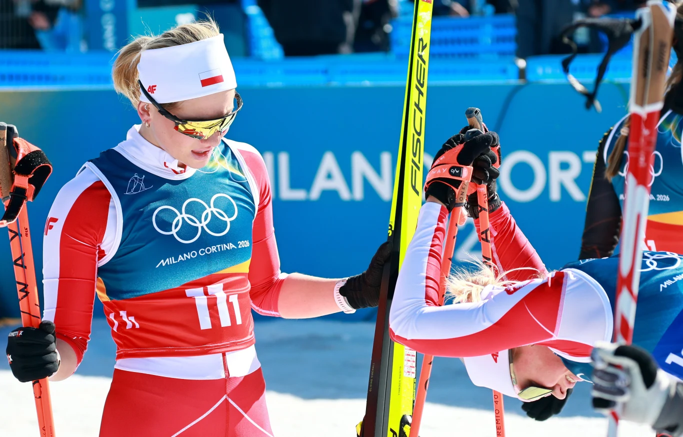 Izabela Marcisz (po lewej) i Monika Skinder Dwie narciarki biegowe w strojach reprezentacyjnych, z widocznymi numerami i logo igrzysk olimpijskich Milano Cortina 2026, jedna z zawodniczek pochyla się zmęczona po rywalizacji, druga dotyka jej ramienia.