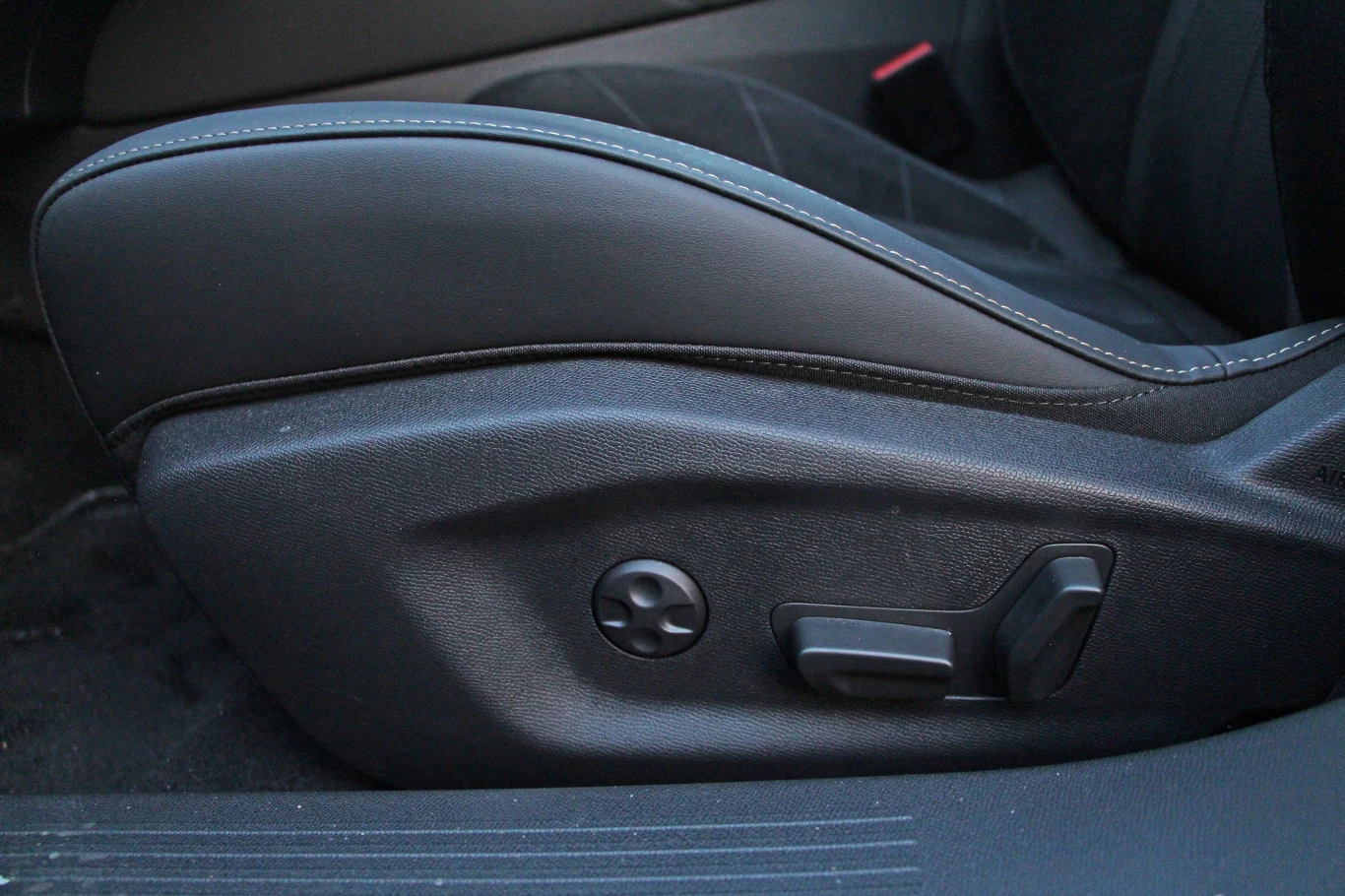 Pełna elektryczna regulacja foteli? Nic z tego - DS No4 z napędem elektrycznym zawsze ma ręczną regulację wzdłużną Boczny widok czarnego fotela samochodowego z widocznymi przyciskami i pokrętłami do regulacji ustawienia siedzenia.