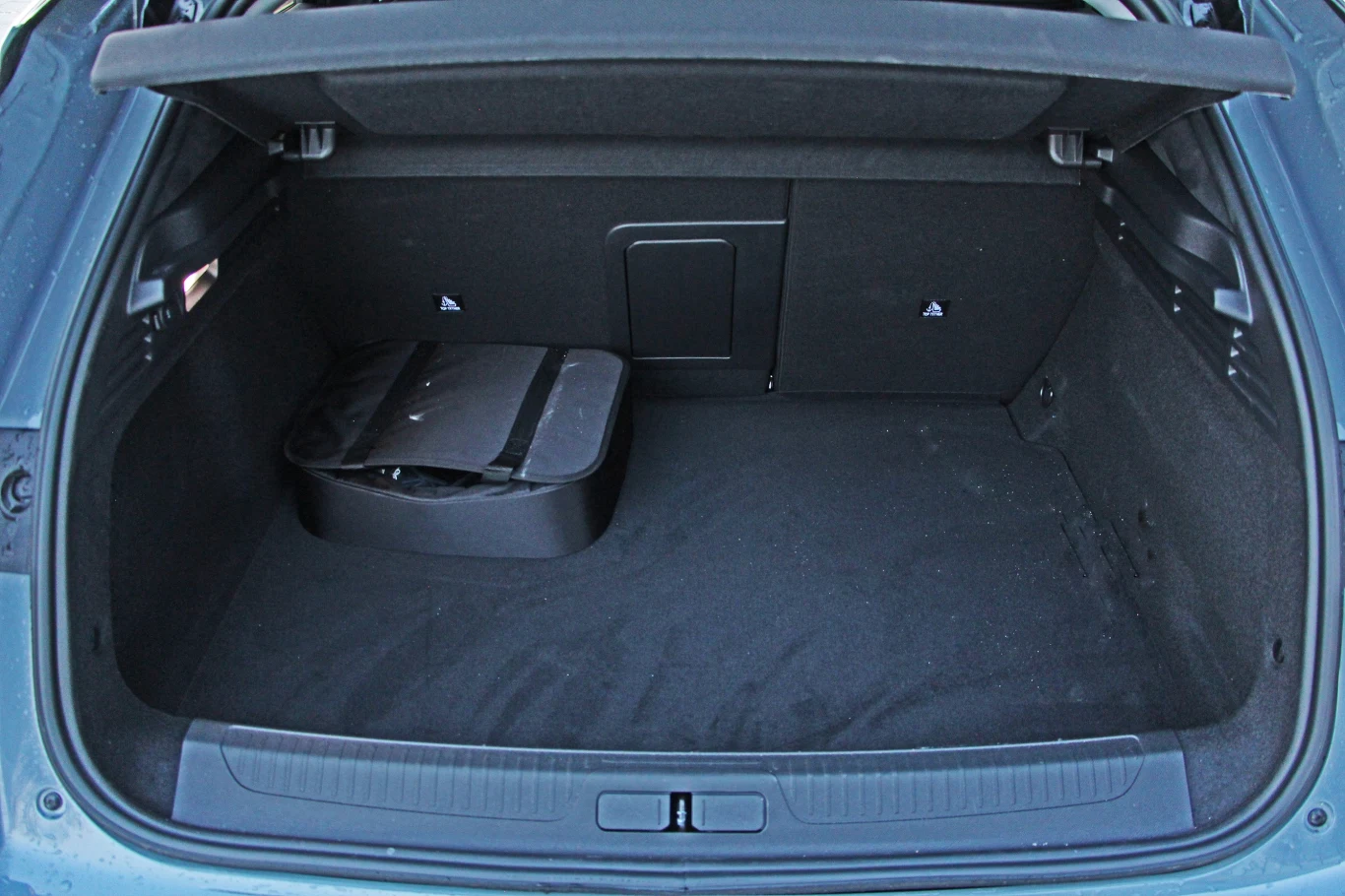 Bagażnik DS No4 E-Tense jest mniejszy niż w wersji czysto spalinowej Otwarty bagażnik samochodu o dużej powierzchni załadunkowej, po lewej stronie znajduje się torba lub organizer; podłoga i wnętrze bagażnika są czyste i zadbane.