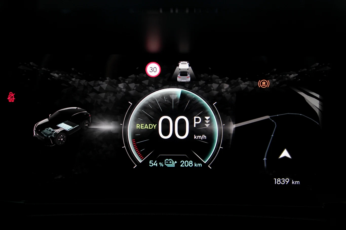 DS No4 po liftingu ma większy ekran wskaźników z możliwością dowolnego ustawienia tego, co wyświetla się po prawej i lewej stronie. Można skonfigurować kilka widoków i szybko się między nimi przełączać Cyfrowy panel wskaźników samochodu elektrycznego wyświetlający prędkość 0 km/h, poziom naładowania baterii na 54%, zasięg 208 km oraz informacje o ograniczeniu prędkości do 30 km/h i przebiegu 1839 km.
