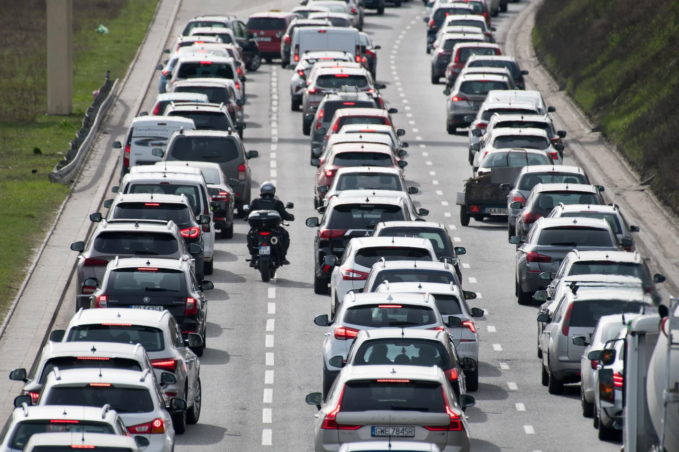 Remonty na głównych trasach w Niemczech. Duże korki i objazdy dla kierowców. Korek uliczny na autostradzie. Samochody i motocyklista między pasami ruchu.