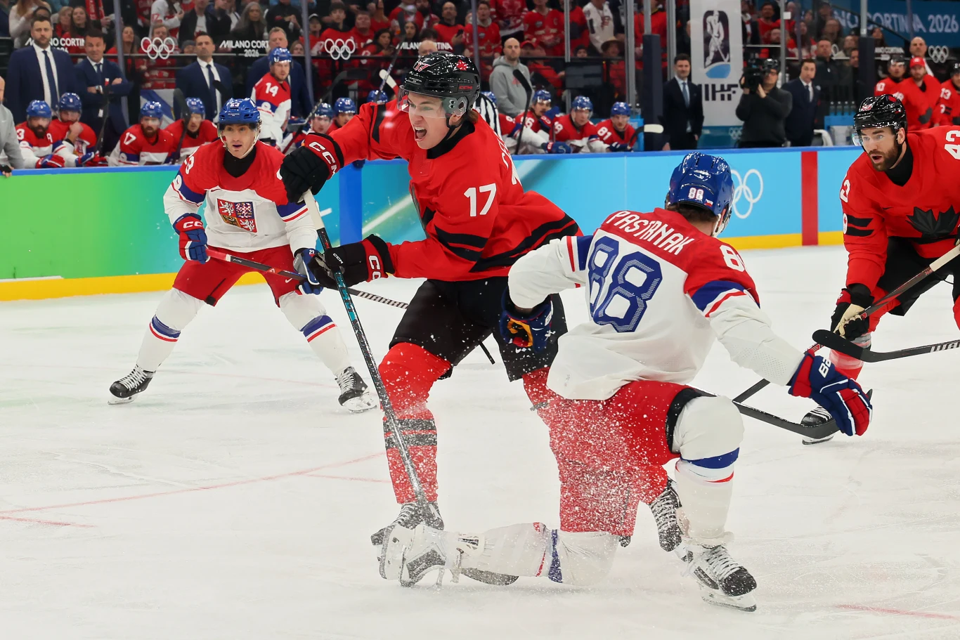 Kadr z ćwierćfinałowego meczu ZIO Kanada - Czechy Zawodnicy reprezentacji Kanady i Czech w trakcie dynamicznej rozgrywki hokeja na lodzie, ostre starcie o krążek na tle tłumu kibiców i olimpijskich symboli.