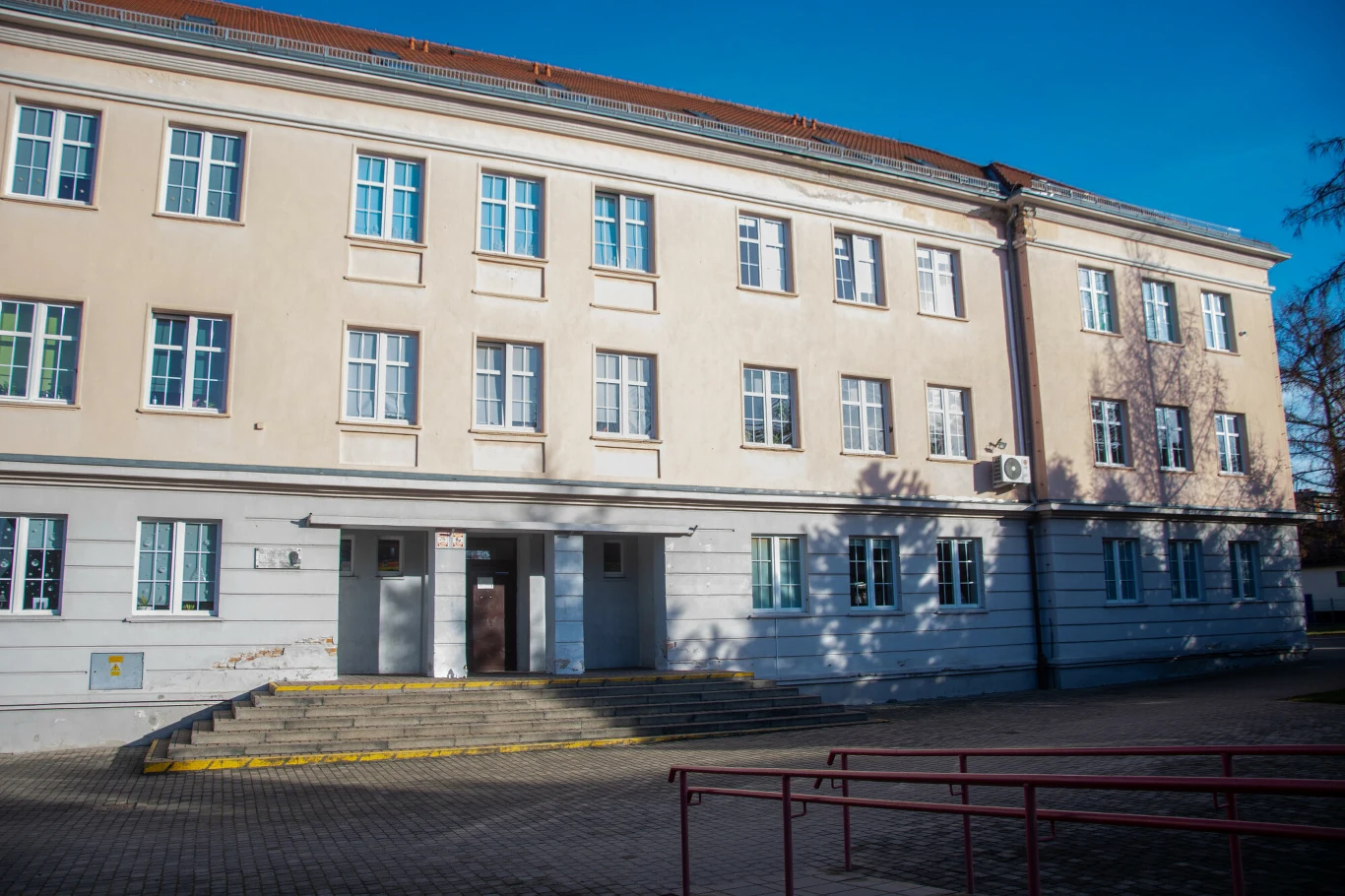 Kuratorium reaguje po śmierci 11-letniej Danusi. W Szkole Podstawowej nr 10 w Jeleniej Górze (na zdjęciu) wykryto liczne uchybienia Trzypiętrowy budynek szkolny o jasnej elewacji, liczne prostokątne okna i schody prowadzące do głównego wejścia, przed obiektem szeroki chodnik z barierkami, widoczna część placu.