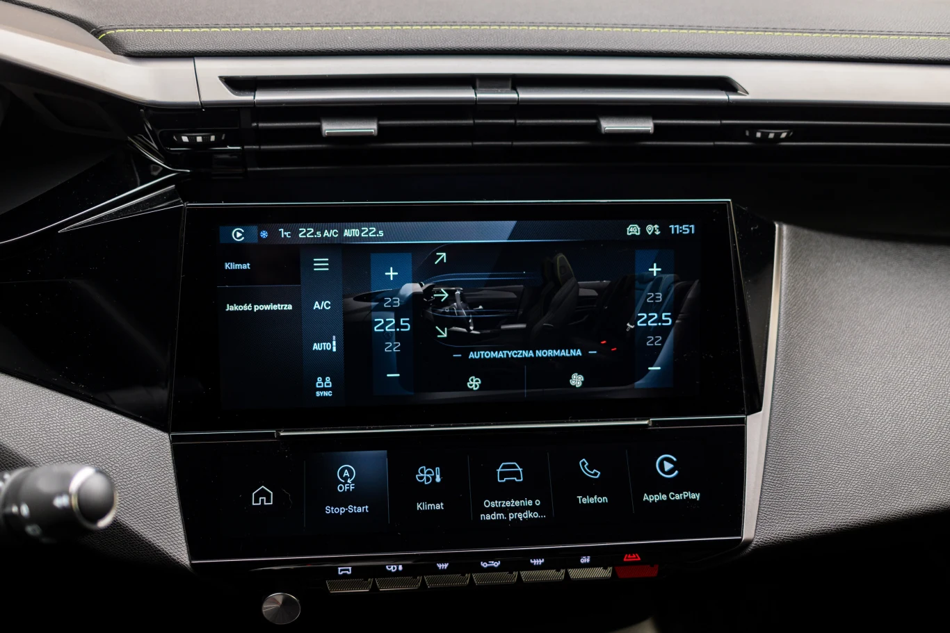 Dotykowy ekran systemu multimedialnego i klimatyzacji samochodu z wyświetlonymi ustawieniami temperatury, klimatyzacji oraz dodatkowymi funkcjami jak nawigacja, telefon i podgrzewanie siedzeń.