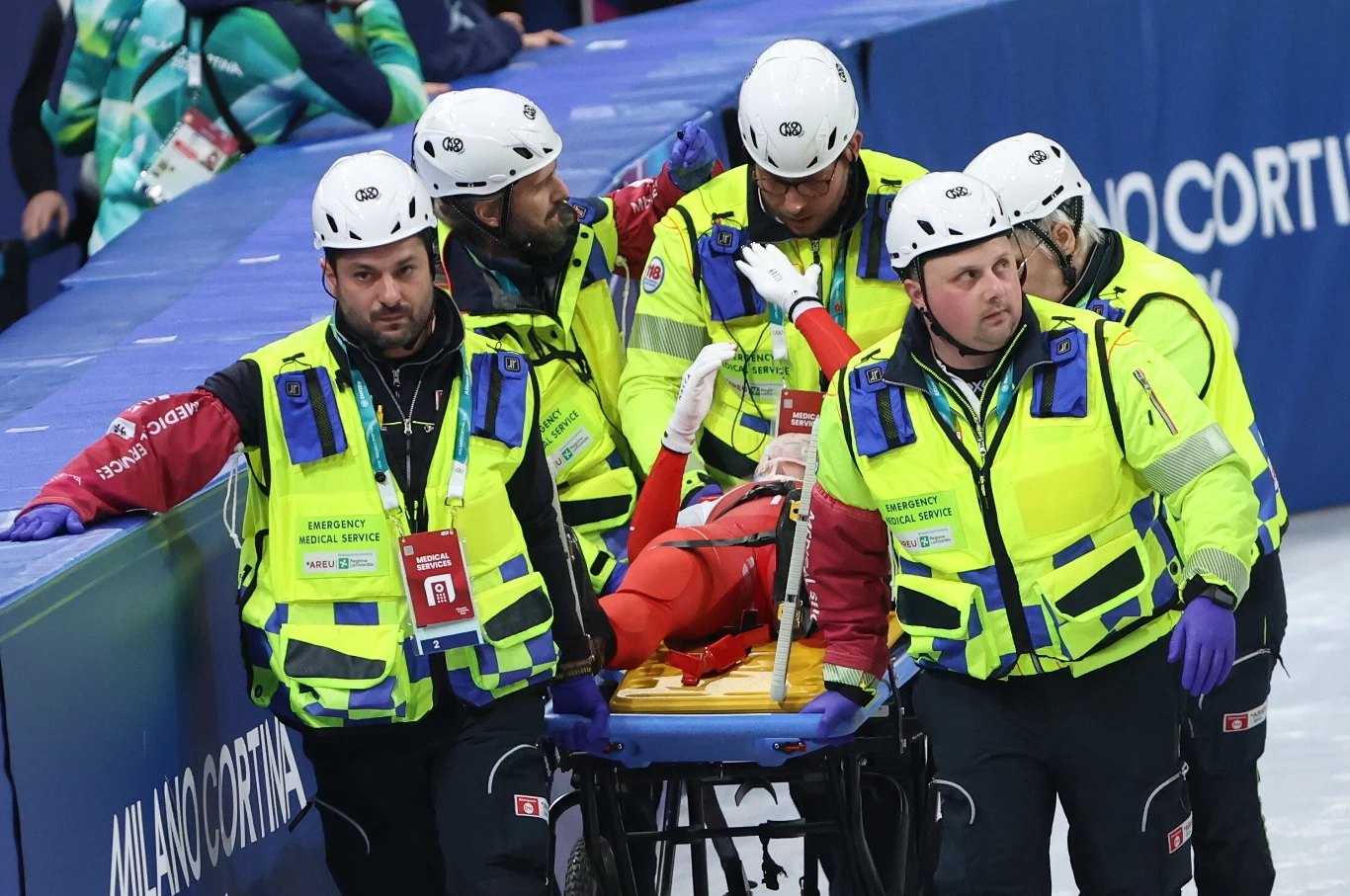 Kamila Sellier na noszach Ratownicy medyczni w żółtych kamizelkach transportują sportowca na noszach po wypadku podczas zawodów, wokół znajdują się oficjalne oznaczenia wydarzenia sportowego.