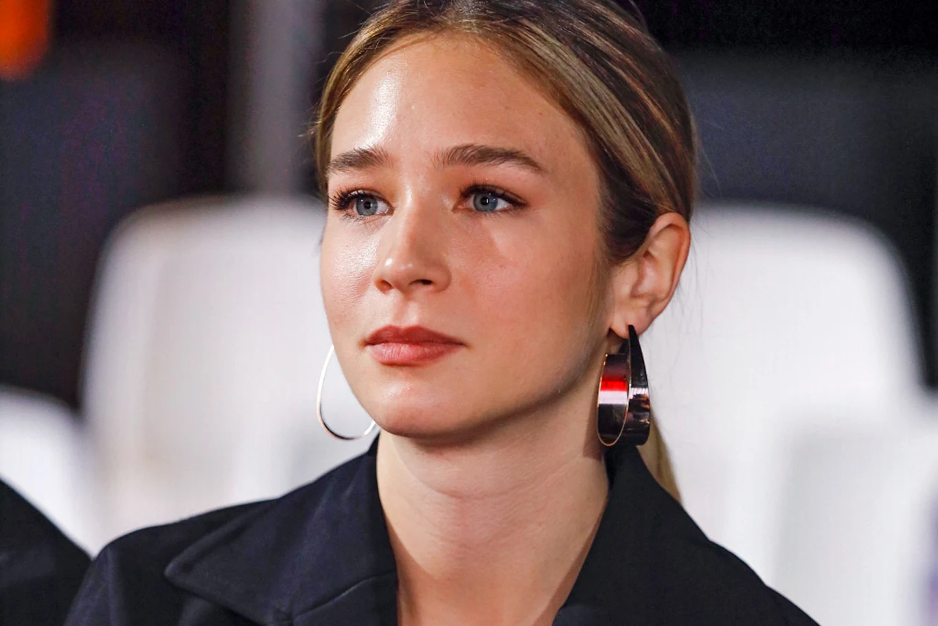 Zofia Wichłacz Młoda kobieta o jasnych włosach spiętych do tyłu, duże srebrne kolczyki koła, subtelny makijaż, wyraz twarzy neutralny, tło rozmyte w jasnych kolorach.