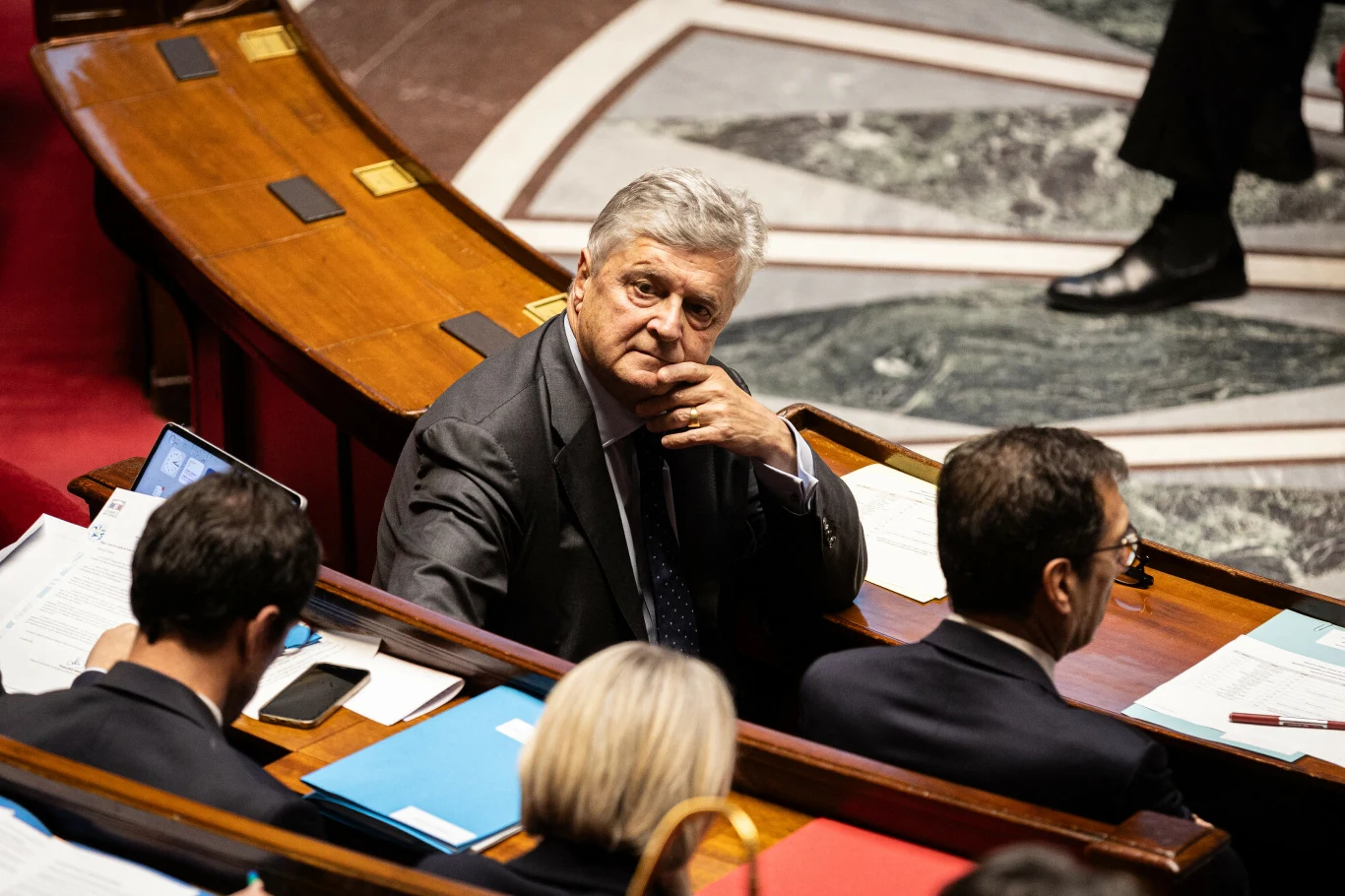 UE odpowie na cła USA? Francja wskazuje na możliwości reakcji Starszy mężczyzna w garniturze siedzi w ławach parlamentarnych, spogląda uważnie w stronę fotografa, wokół niego znajdują się inni uczestnicy posiedzenia zajęci przeglądaniem dokumentów.