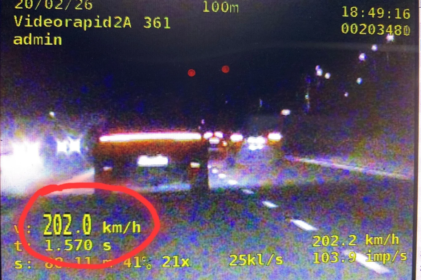 W momencie pomiaru radiowóz jechał 202 km/h Ekran z policyjnego radaru zarejestrował samochód jadący z prędkością 202 km/h nocą na oświetlonej drodze, na wyświetlaczu widoczne są dane pomiarowe oraz czerwone podkreślenie prędkości.