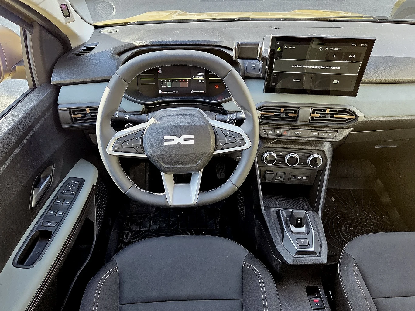 We wnętrzu Sandero pojawiła się m.in. nowa kierownica i ekran dotykowy o przekątnej 10-cali. Opcjonalnie auto może mieć automatyczną skrzynię z łopatkami przy kierownicy i nawigację online Wnętrze nowoczesnego samochodu z widoczną kierownicą z logo, cyfrowym panelem wskaźników, dużym ekranem dotykowym na konsoli centralnej, panelem klimatyzacji oraz automatyczną skrzynią biegów.