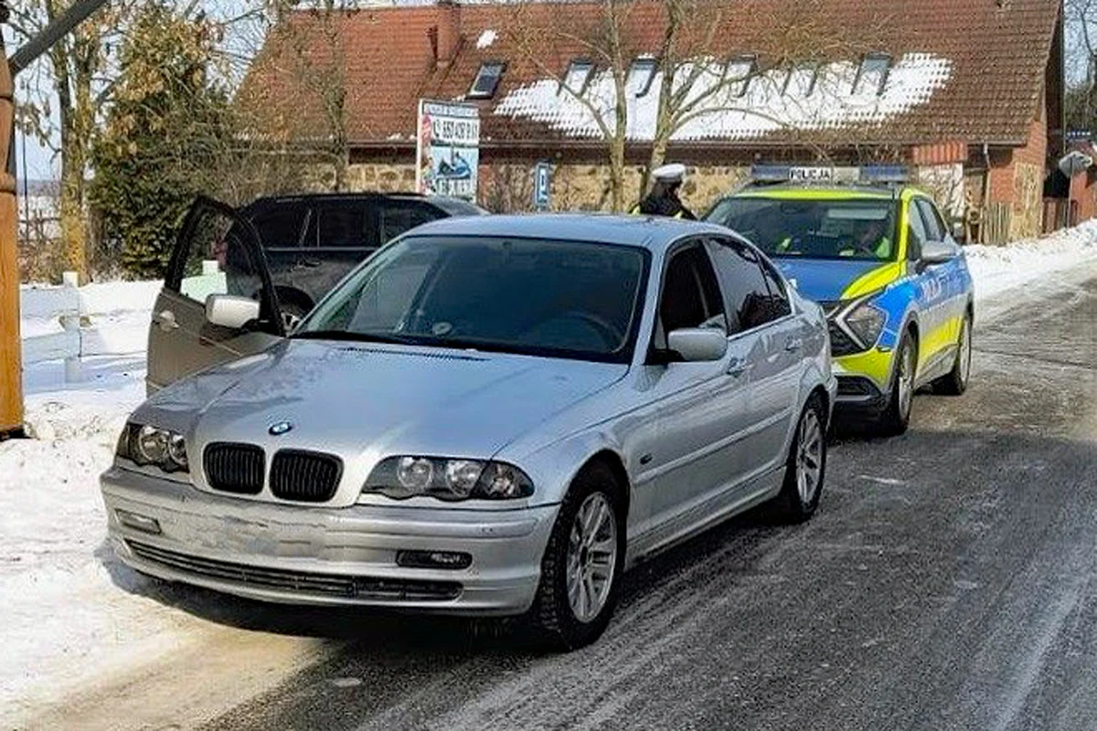 Policjanci przeprowadzili wzmożone kontrole drogowe w okolicach jeziora Śniardwy Srebrny samochód BMW zatrzymany przez radiowóz policyjny na ośnieżonej drodze, przy otwartych drzwiach kierowcy widoczny funkcjonariusz policji wykonujący czynności służbowe.