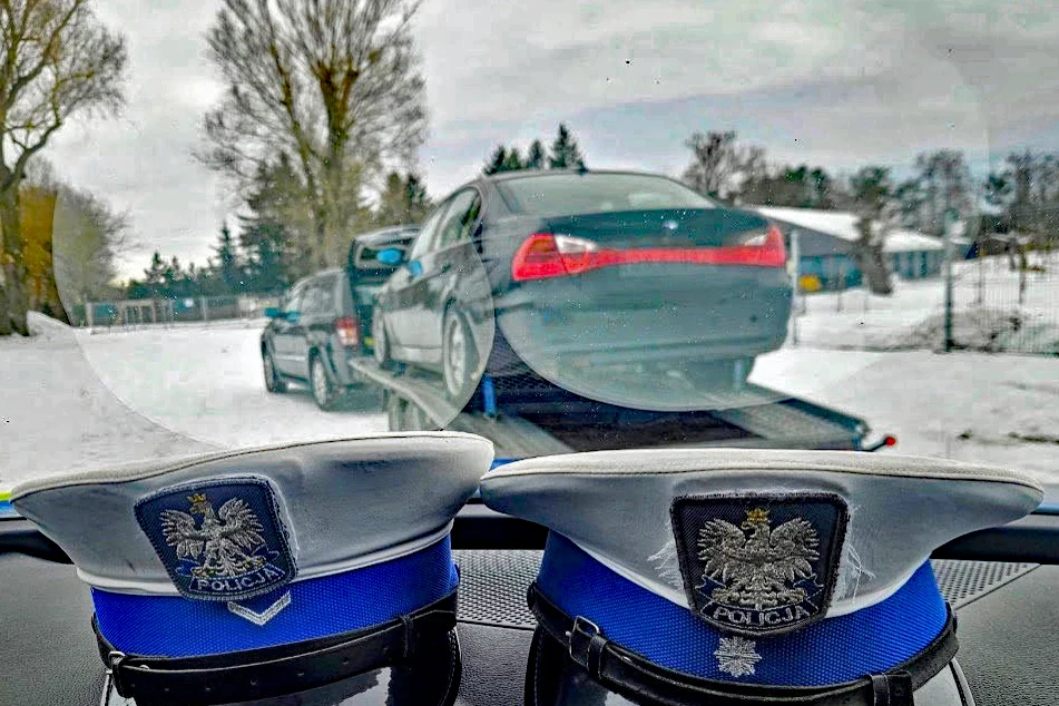 Zdarzali się nawet kierowcy, którzy wieźli tylnonapędowe auta na lawetach Dwa policyjne czapki leżące na desce rozdzielczej samochodu, przez szybę widać lawetę z transportowanym pojazdem osobowym w zimowej scenerii.