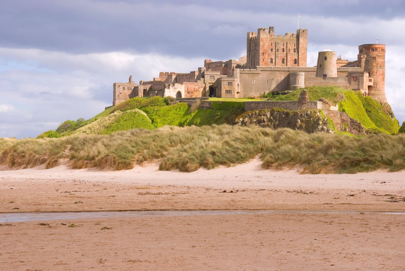 Bamburgh Beach zwyciężyła w kategorii "One of a Kind". Kamienny zamek położony na wzgórzu, otoczony murami i zielenią, z widocznymi wieżami i bastionami, u jego podnóża rozpościera się szeroka, piaszczysta plaża z niewielkimi kępami traw.