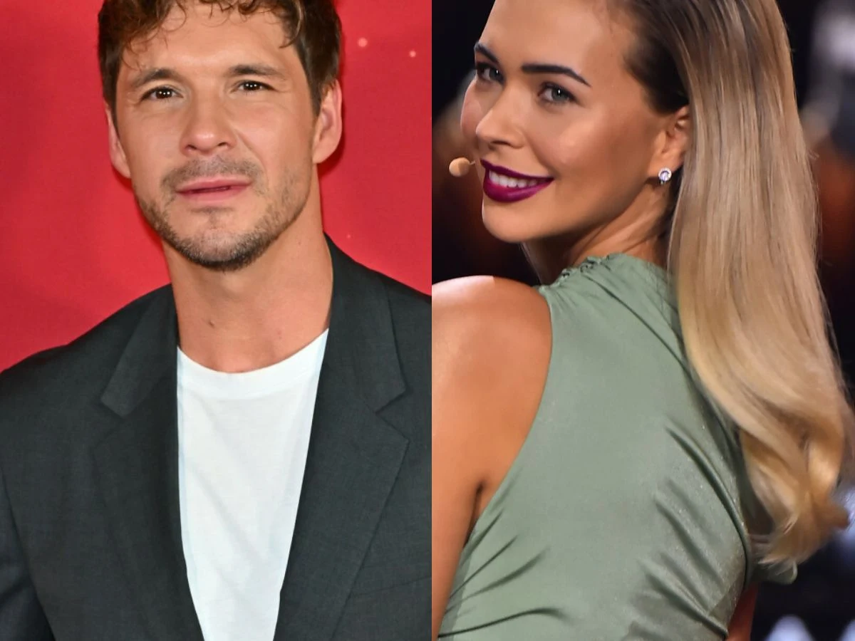 Mikołaj Roznerski, Sandra Kubicka Dwie osoby, mężczyzna w ciemnej marynarce oraz kobieta w zielonej sukni z długimi, rozjaśnionymi włosami i wyrazistym makijażem, uśmiechają się, pozując na tle czerwonego tła.