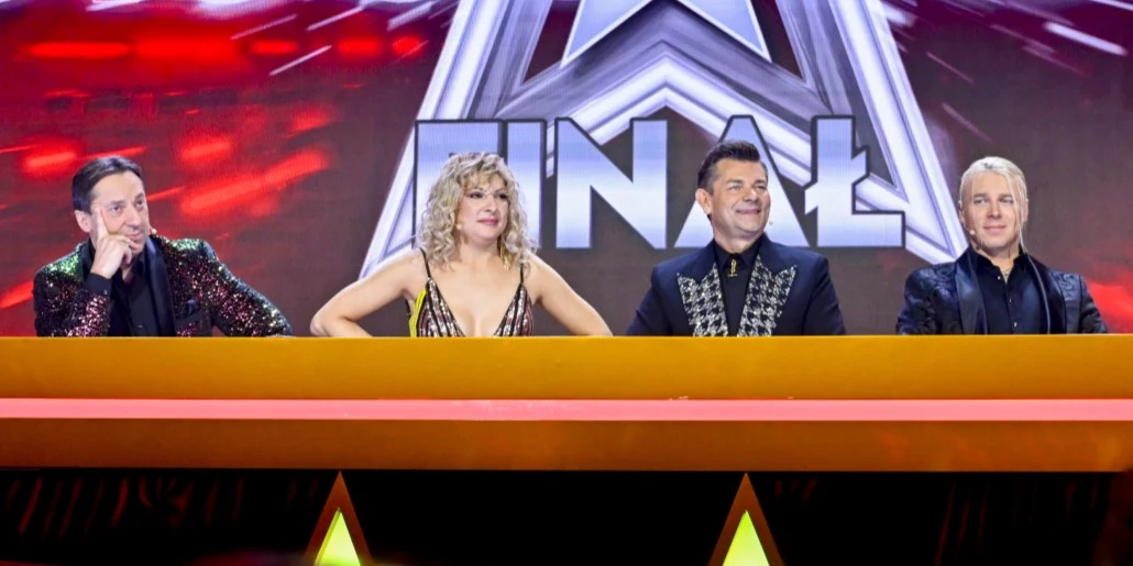 Jurorzy 9. edycji "Disco Star": Marcin Miller, Magdalena Narożna, Zenek Martyniuk i Skolim Czwórka jurorów siedzi za pomarańczowym stołem na tle napisu finał oraz jasnych świateł, każda osoba ubrana elegancko, skupione wyrazy twarzy.