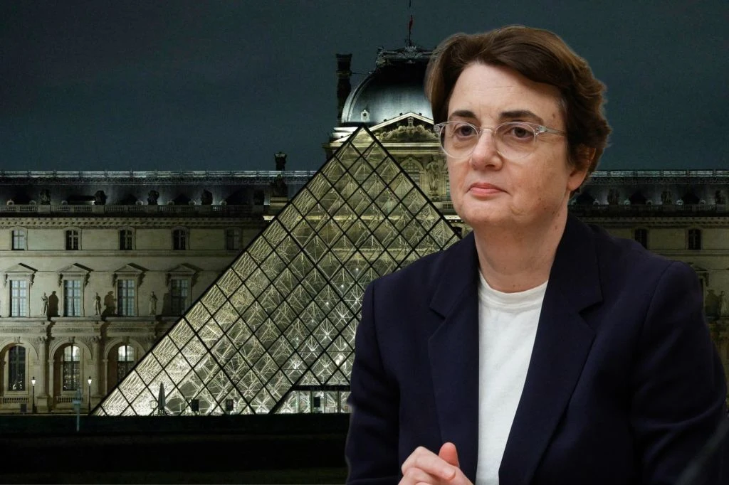 Dyrektor Luwru Laurence des Cars zrezygnowała ze stanowiska Kobieta w okularach i eleganckiej marynarce na tle podświetlonej piramidy Luwru w Paryżu, widoczna architektura muzeum nocą.