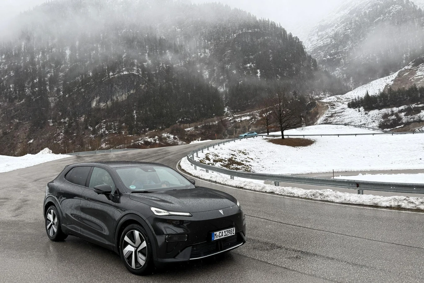 Współczynnik oporu powietrza w Changanie Deepal S05 wynosi 0,25. Czarny samochód elektryczny stoi na zakręcie górskiej drogi otoczonej śniegiem, w tle góry pokryte częściowo śniegiem i spowite mgłą.