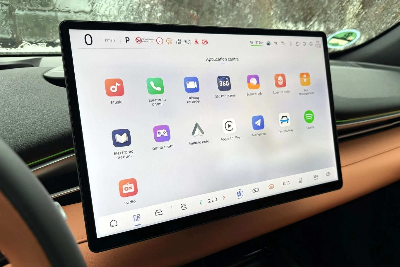 Do obsługi multimediów służy ekran o przekątnej 15,4 cala. Z jego poziomu obsługujemy miażdżącą większość funkcji w tym aucie. Na szczęście można go przekręcić w stronę kierowcy. Duży ekran dotykowy w nowoczesnym samochodzie wyświetlający interfejs aplikacji z ikonami muzyki, telefonu, nawigacji, przeglądarki internetowej oraz innych multimediów i usług. W tle widoczna deska rozdzielcza oraz fragment kierownicy.