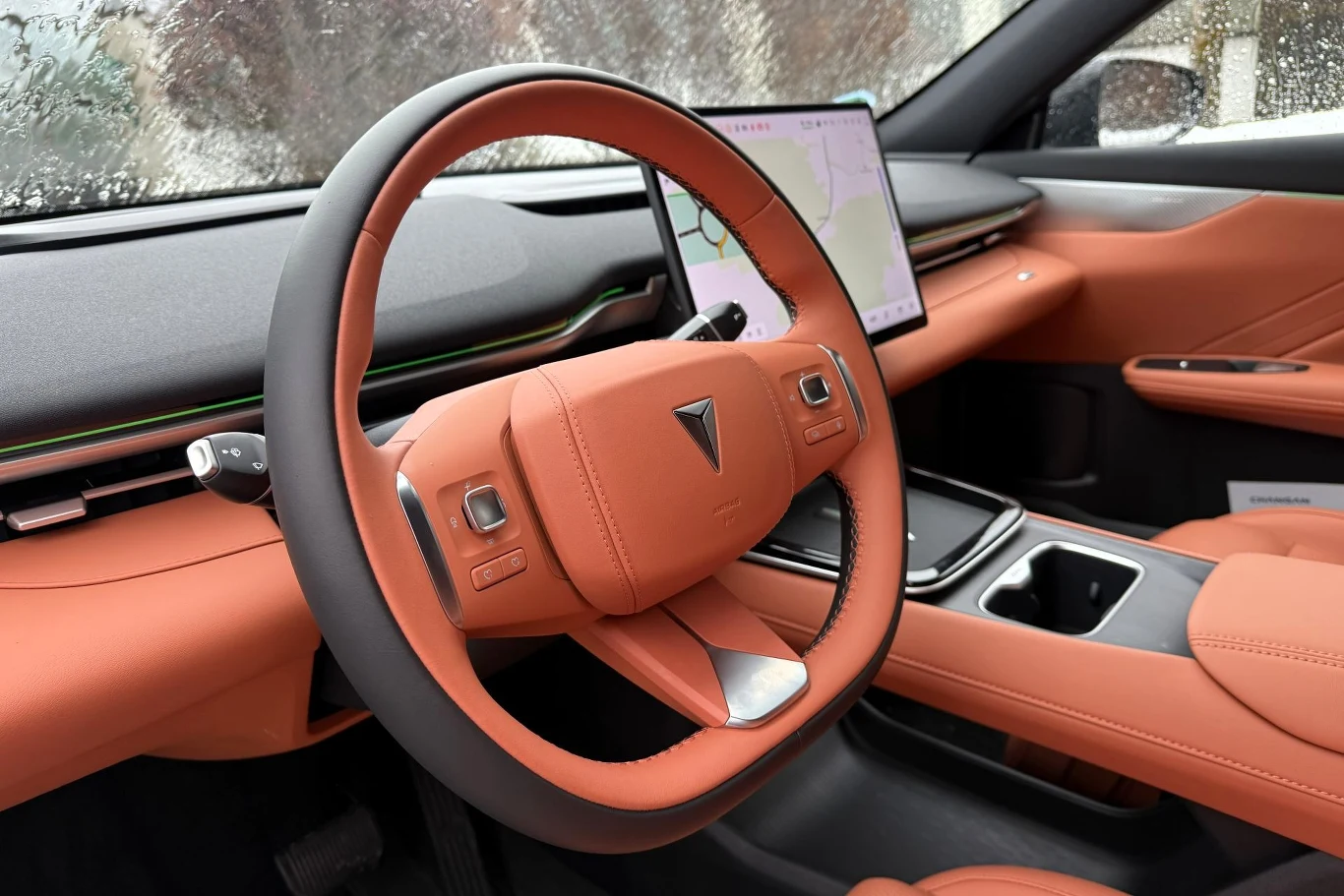 Przed kierowcą nie ma ekranu wskaźników. Informacje dotyczące np. prędkości, z jaką się poruszamy, znajdują się na ekranie multimediów. Opcjonalnie możemy zdecydować się na wyświetlacz przezierny. Wnętrze nowoczesnego samochodu z pomarańczową skórzaną tapicerką, dużym ekranem dotykowym na desce rozdzielczej oraz kierownicą wykończoną skórą w tym samym kolorze.
