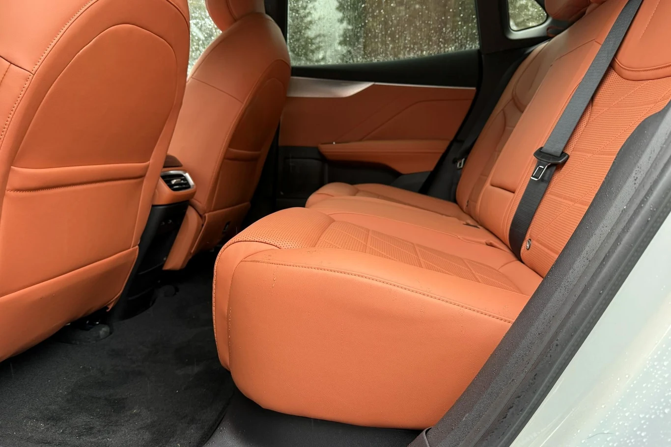 Przy długości wynoszącej 4,6 metra i rozstawie osi prawie 2,9 m miejsca z tyłu Changana Deepal S05 nie brakuje. Tylny rząd siedzeń samochodu z luksusową, pomarańczową skórzaną tapicerką, widoczne dwa zagłówki, pas bezpieczeństwa, czyste i przestronne wnętrze.