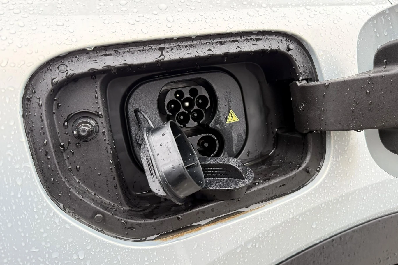 Changana Deepal S05 można ładować prądem stałym o mocy do 200 kW. Port ładowania samochodu elektrycznego z otwartą klapką i widocznymi kroplami deszczu na karoserii.