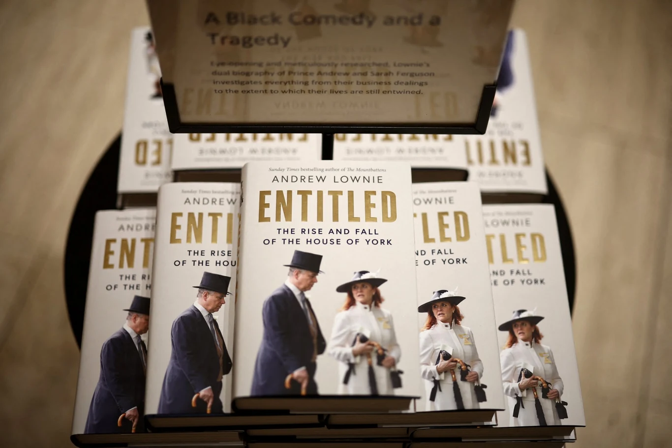 Stos książek autorstwa Andrew Lownie zatytułowanych 'Entitled The Rise and Fall of the House of York' z okładkami ukazującymi elegancko ubranych ludzi w kapeluszach, sfotografowany z góry przy stoisku księgarni.