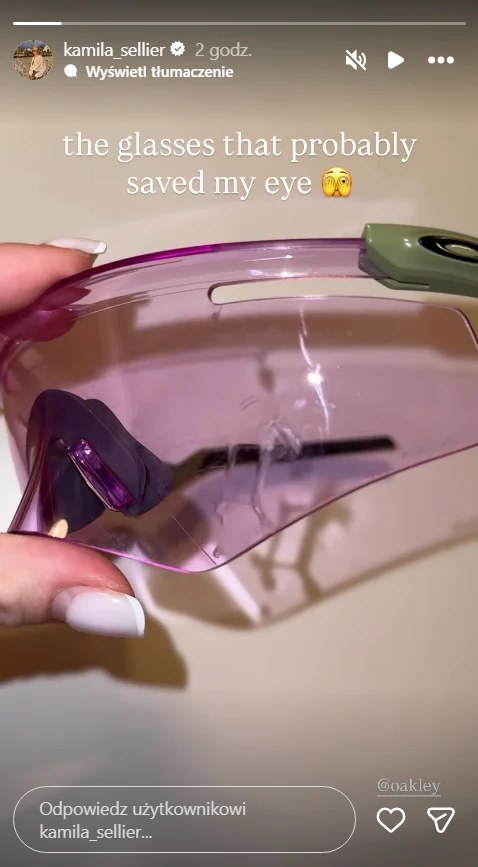 Różowe okulary ochronne trzymane w dłoni, zawierające widoczne uszkodzenie, które świadczy o ich skuteczności w ochronie oka.