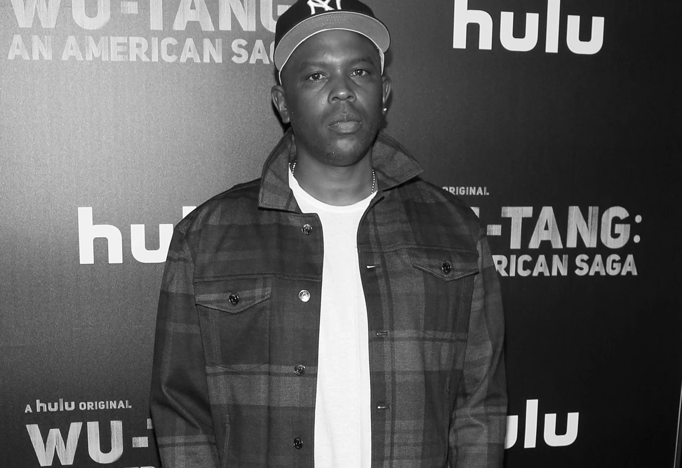 Nie żyje Olivier "Power" Grant Mężczyzna w czapce z daszkiem i rozpiętej kurtce na tle ścianki z logo Hulu oraz tytułem serialu Wu-Tang An American Saga.