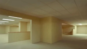 Puste, jasne pomieszczenie o żółtawych ścianach i suficie z płyt, brak mebli, rozproszone światło świetlówek, układ kilku korytarzy i przejść, nieobecność ludzi i personalnych oznaczeń.