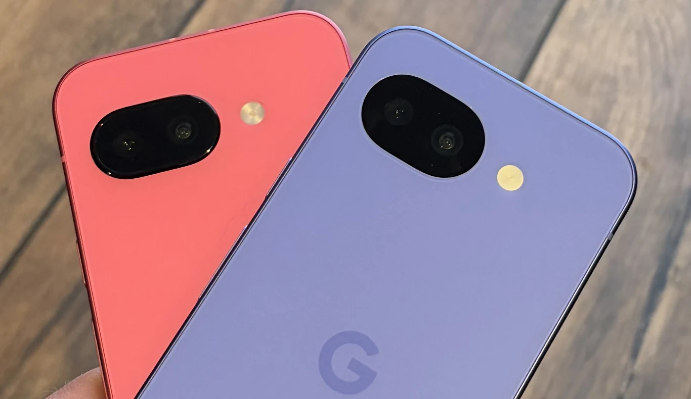 Dwa kolorowe smartfony Google w odcieniach koralowym i fioletowym ułożone są tylnią stroną do góry, wyeksponowane są aparaty fotograficzne i logo G, w tle widoczna jest drewniana powierzchnia.