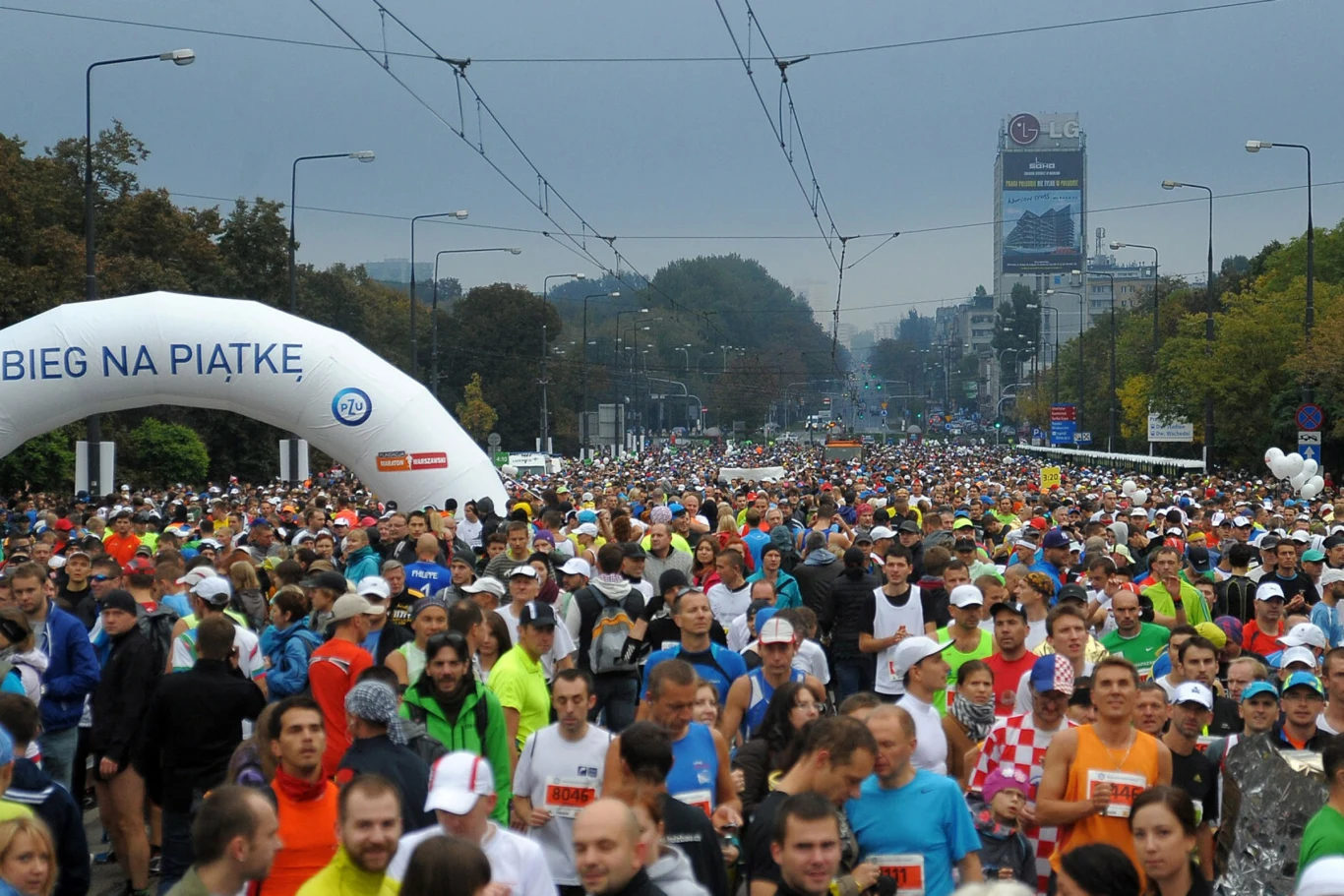 Jeff Galloway zmienił podejście do masowego biegania. Jego metoda treningowa stała się zbawieniem dla milionów miłośników tego rodzaju aktywności Tłum biegaczy startujących w masowej imprezie sportowej na miejskiej ulicy pod biało-niebieskim łukiem z napisem Bieg na piątkę, w tle drzewa oraz charakterystyczne wysokie budynki miasta.