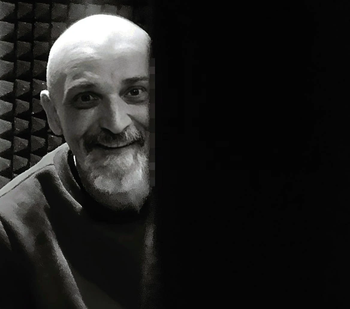 Wojtek "Sęp" Dudziński przez wiele lat był wokalistą grupy Ryczące Dwudziestki Mężczyzna o łysinie i siwej brodzie, uśmiechający się, siedzi w pomieszczeniu z panelami akustycznymi na ścianach. Prawa część zdjęcia jest zaciemniona, zasłaniając połowę jego twarzy.